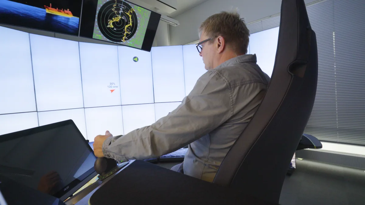 An operator at the console, engine load on the wall in front of him